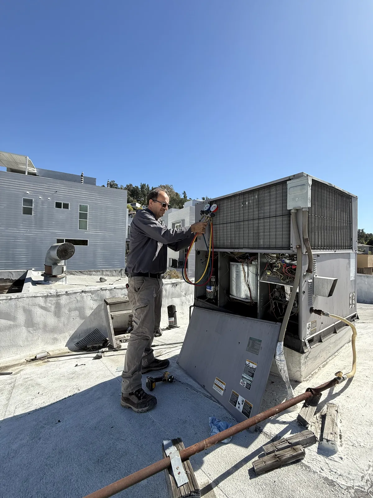 Air Plus HVAC technician checking the controls on an open rooftop unit.