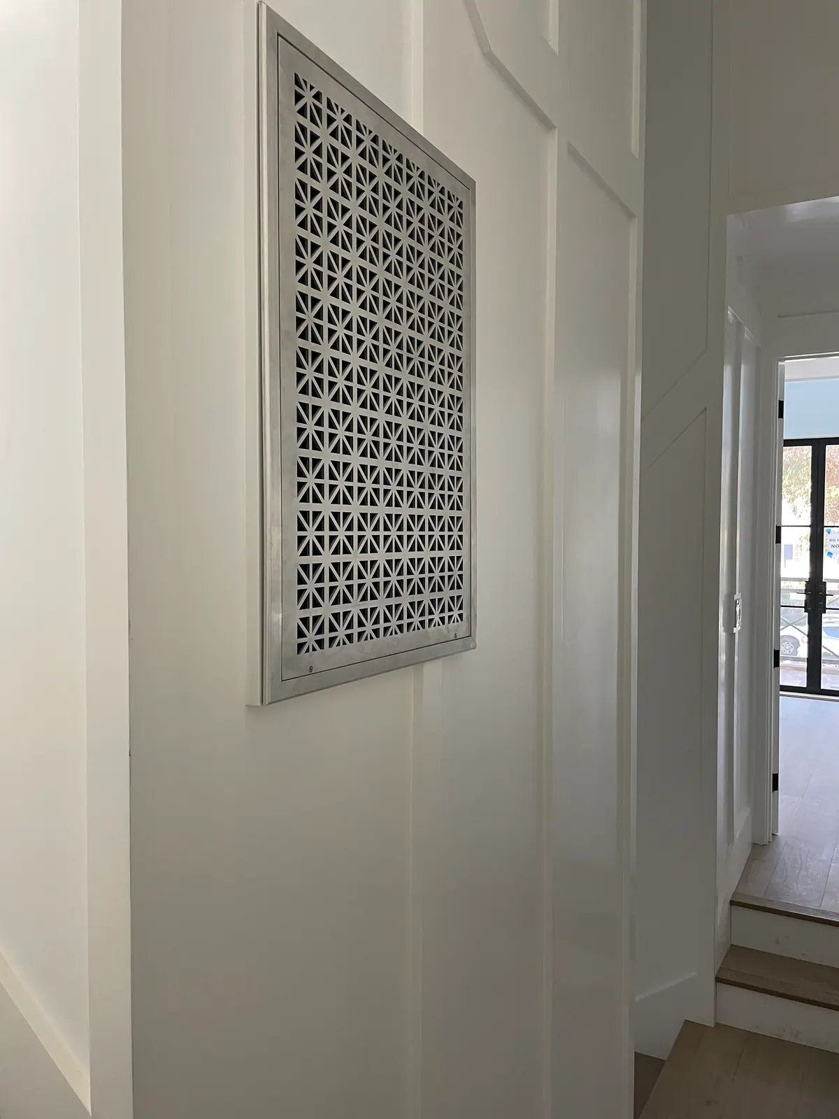 Decorative wall grille on a white paneled wall.