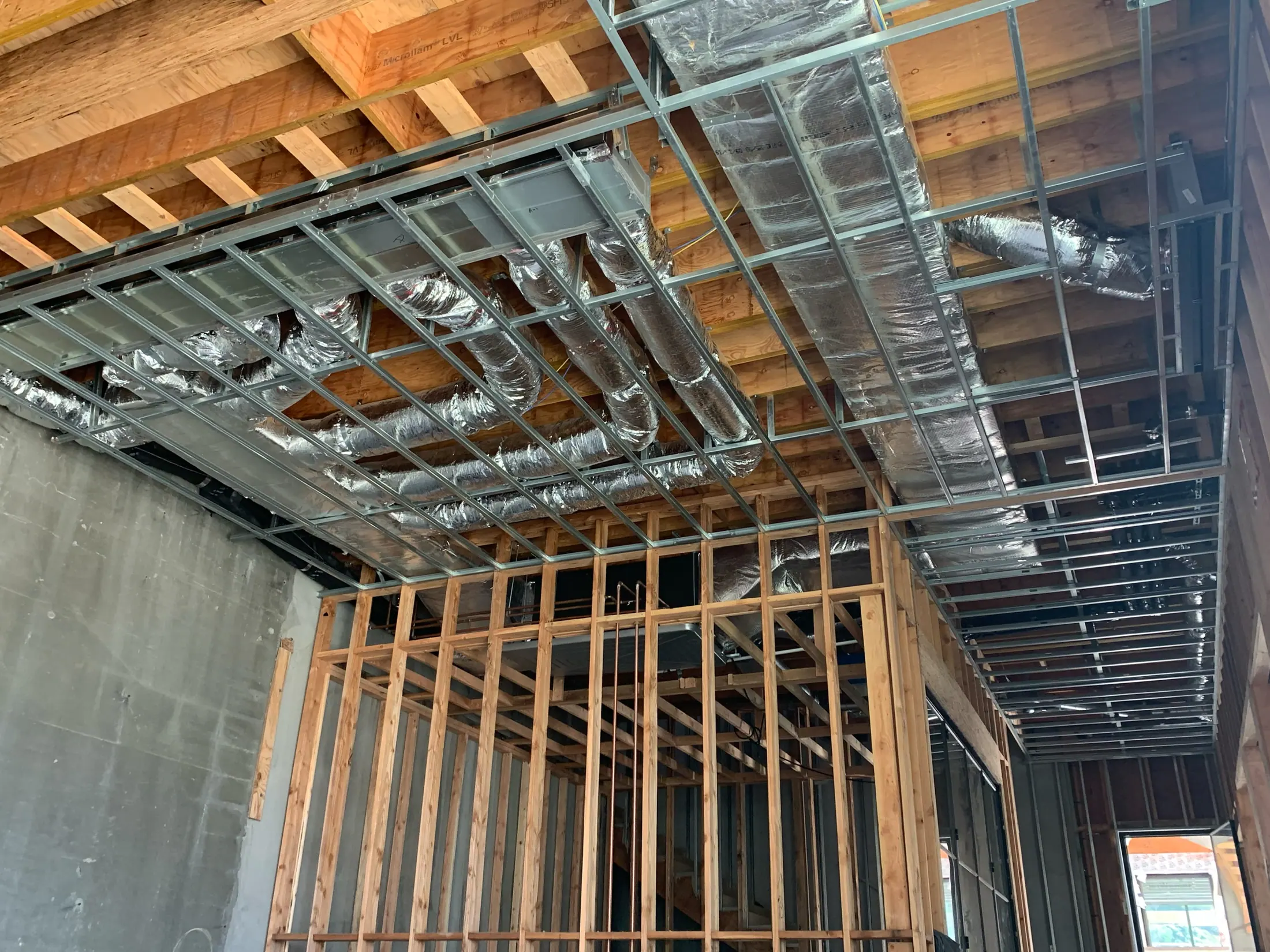 Insulated ductwork run through the ceiling framing of a house under construction.