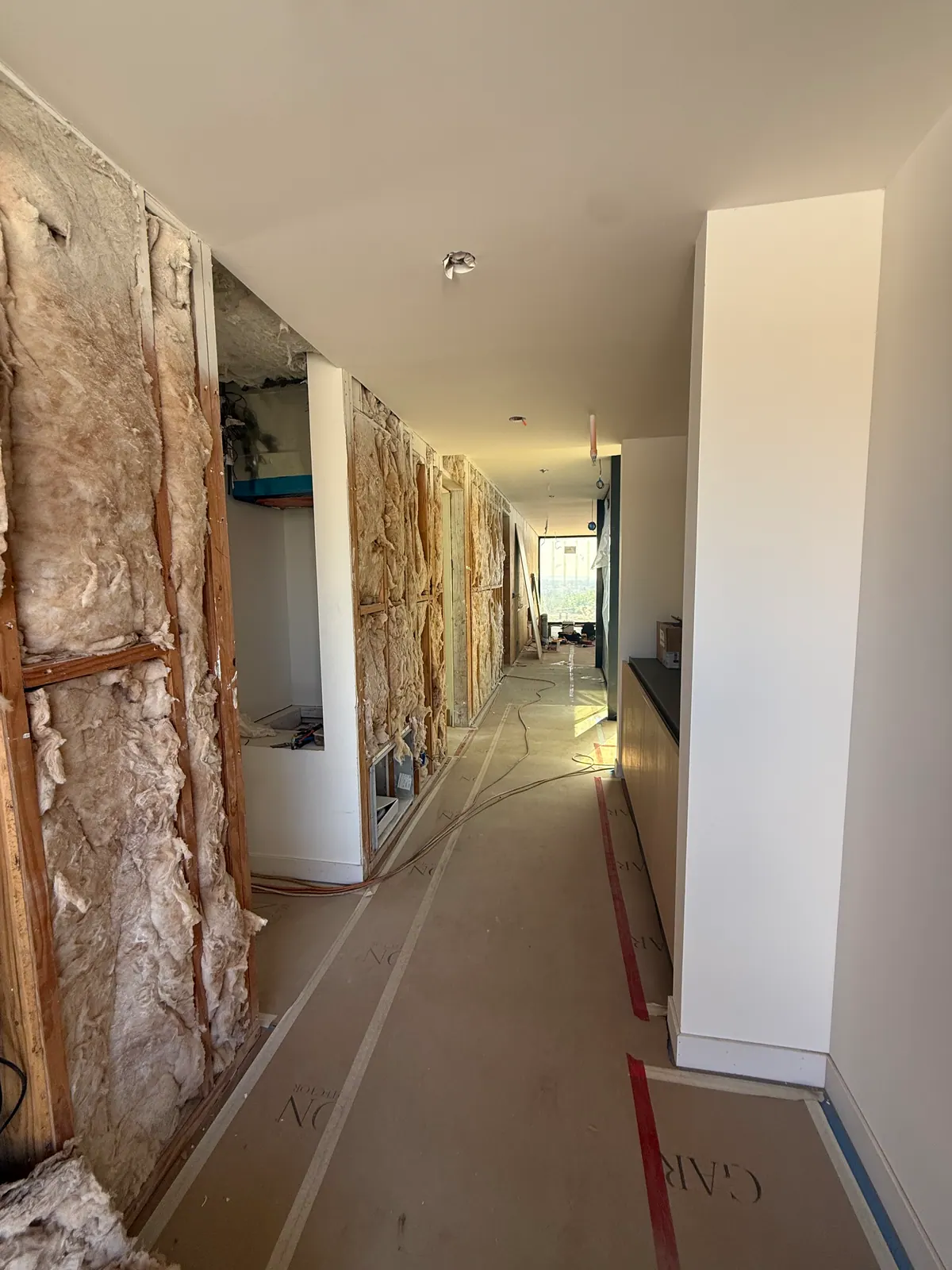 Hallway with paper covering the floor and insulation exposed in the wall.