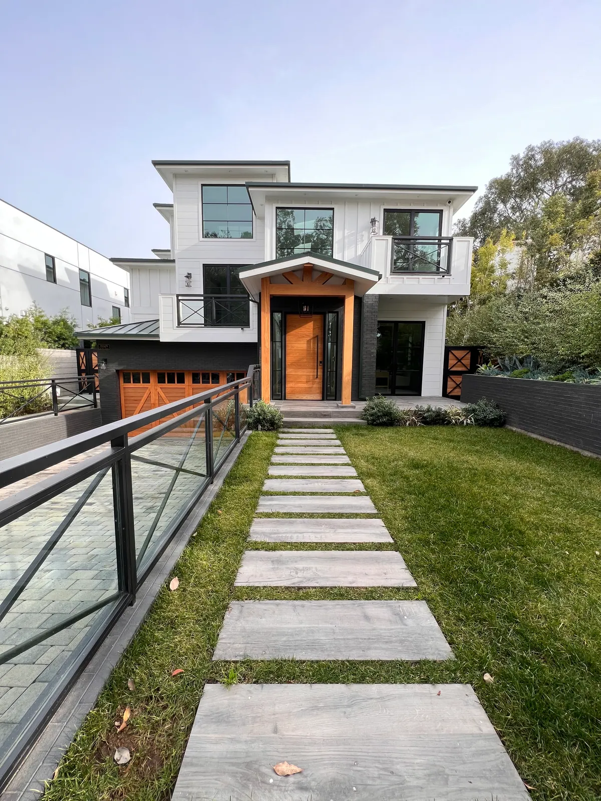 White home with a wood front door, a lawn, and a stepping-stone walkway.