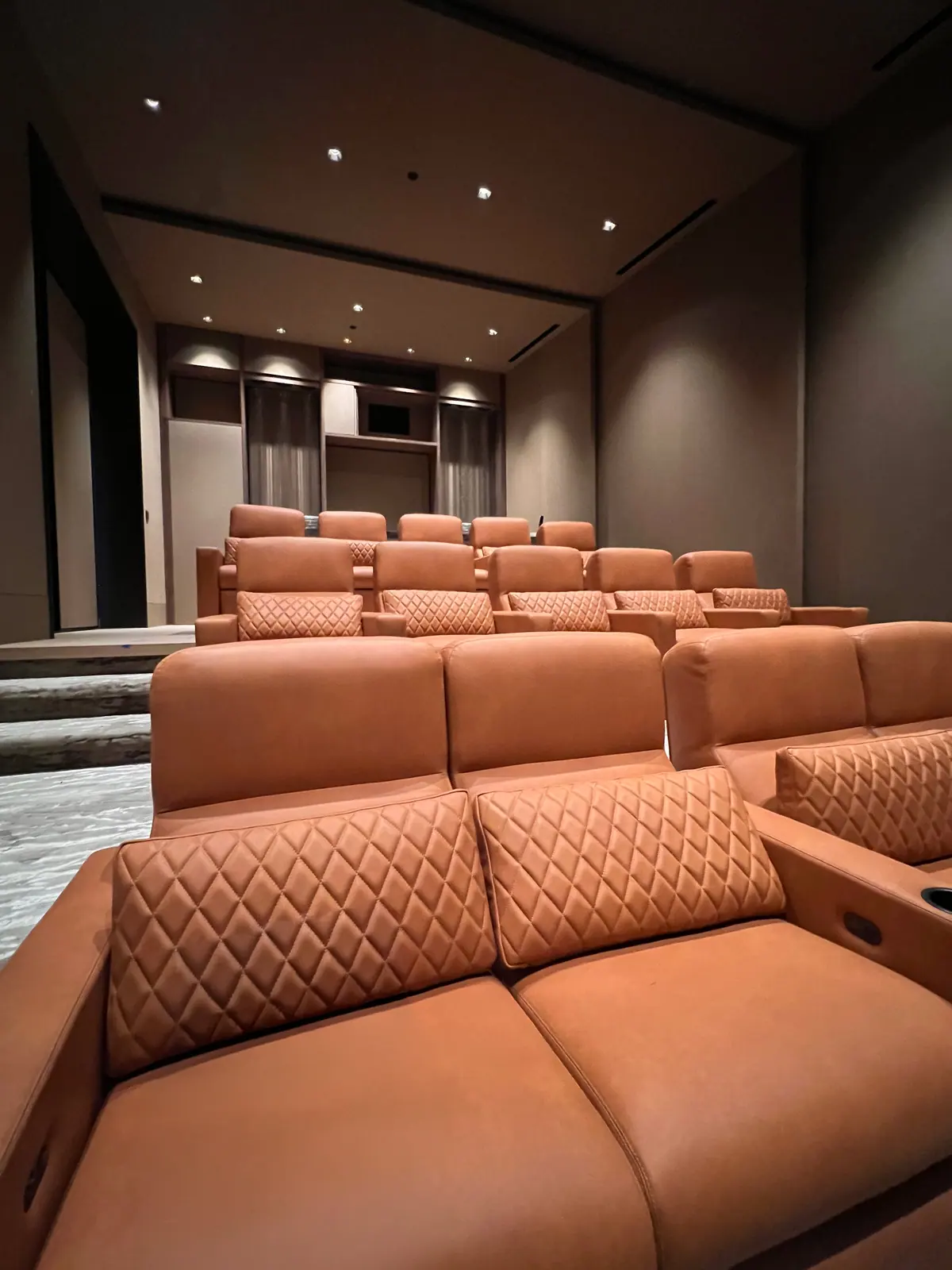 Home theater with tiered tan leather seating.