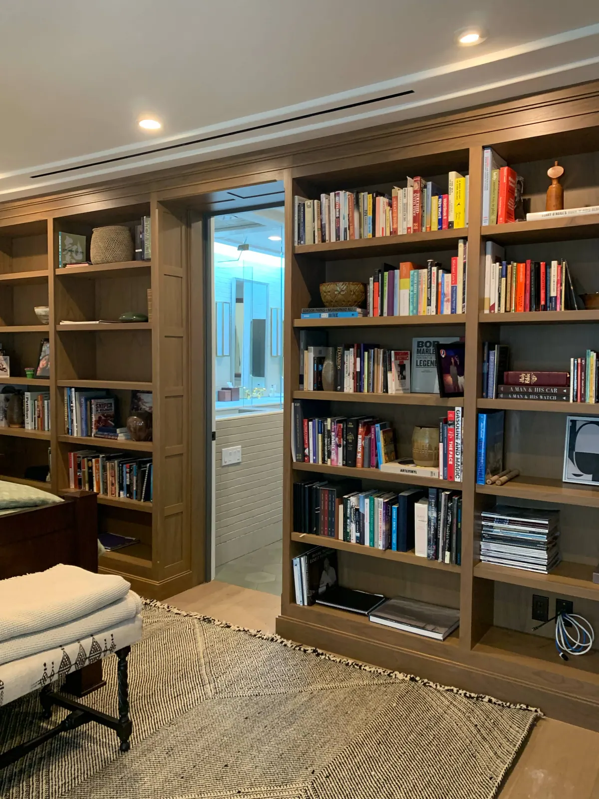 Room with floor-to-ceiling oak bookshelves, a bench, and a rug.