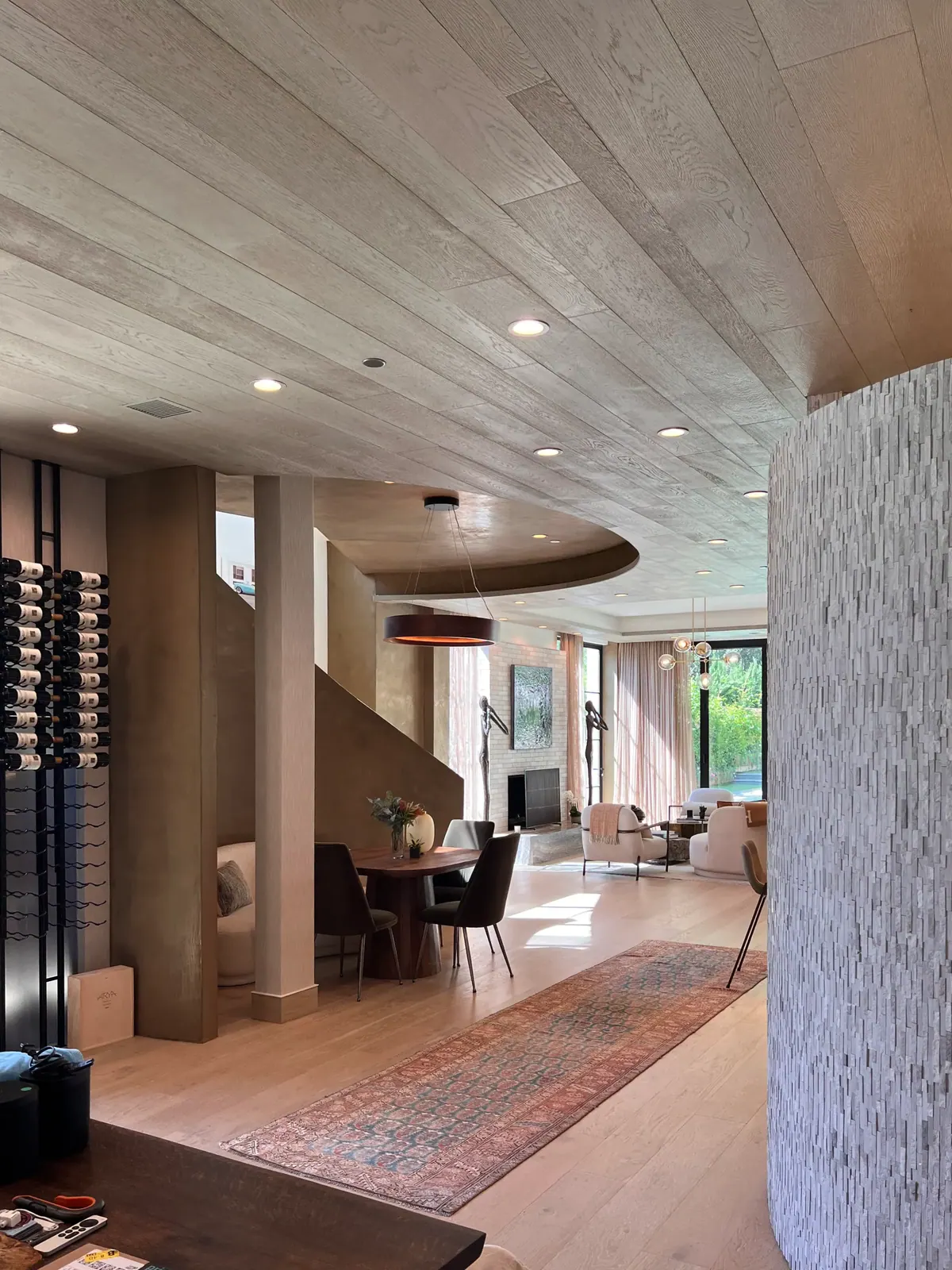 Open living area with a pale plank ceiling, a wine wall, and a rug.