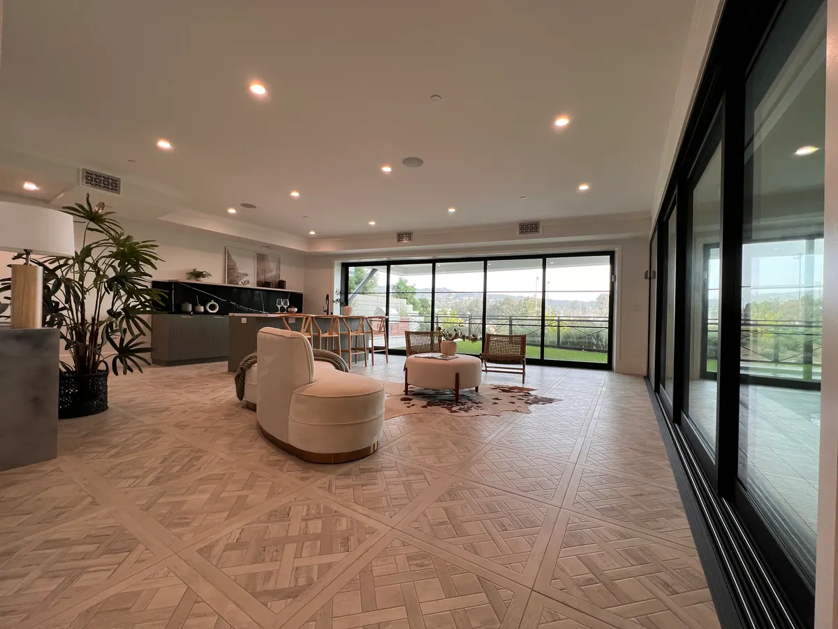 Living room with a patterned wood floor, round chairs, and sliding glass doors to a view.