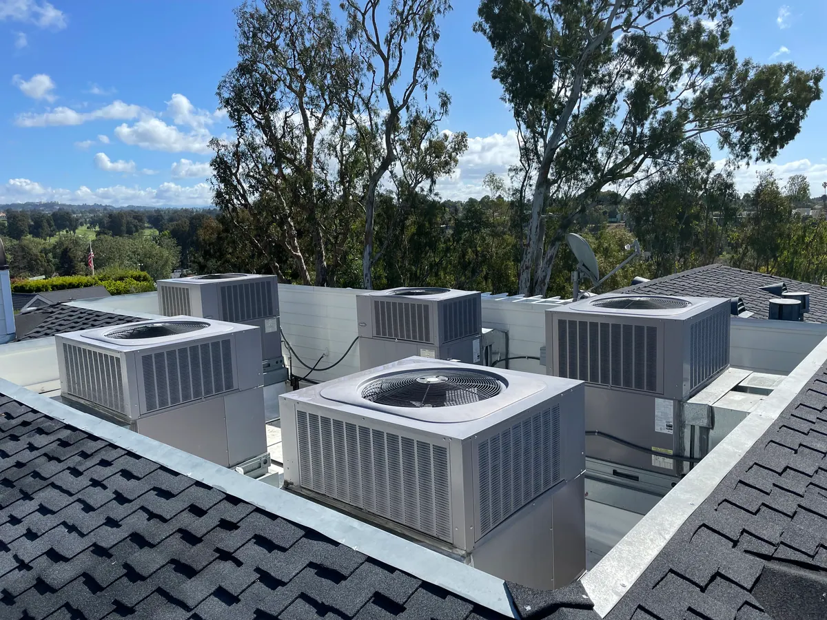 Four rooftop condensers on a sloped shingle roof.