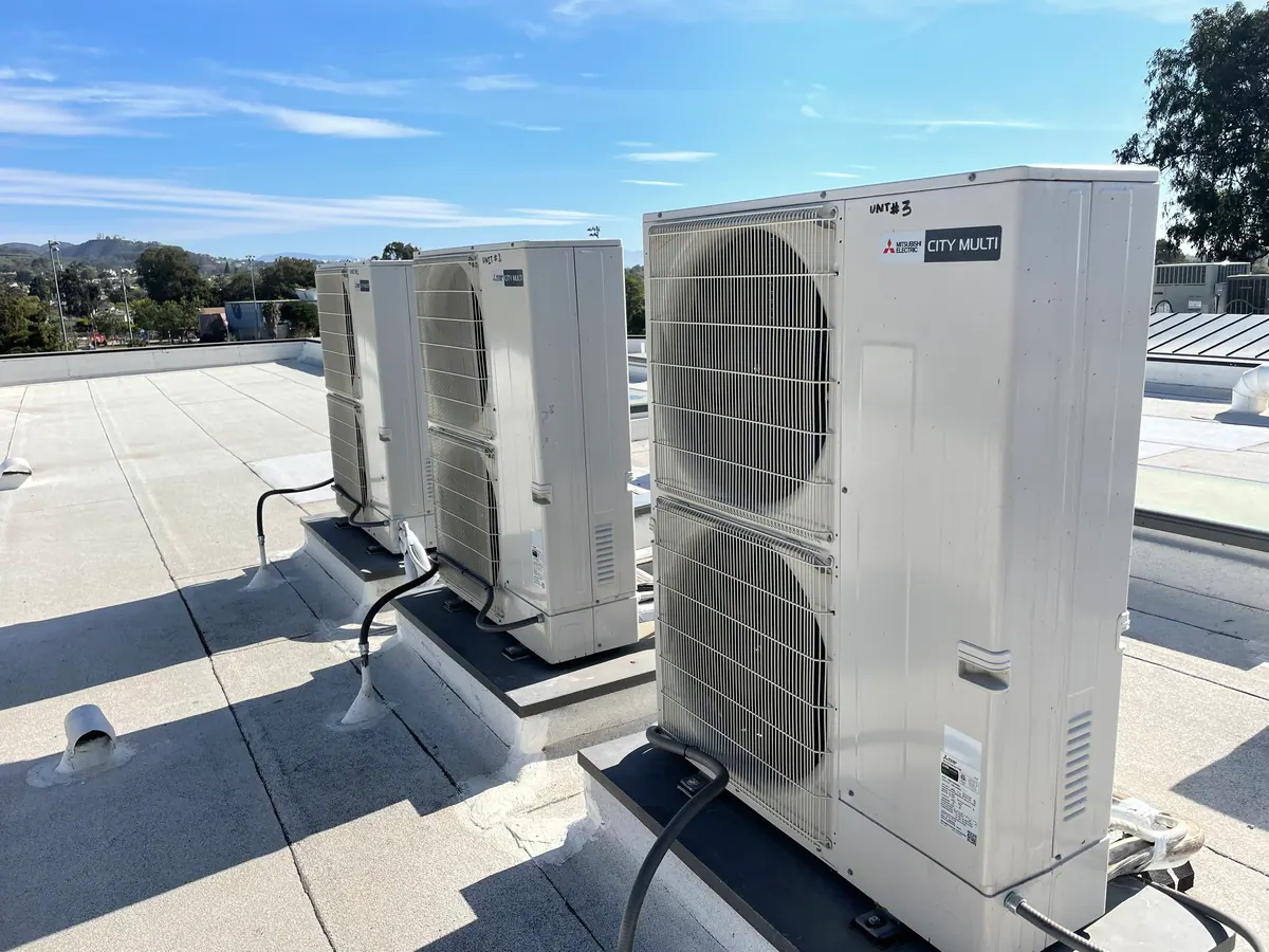 Two outdoor units with large fans on a flat roof.