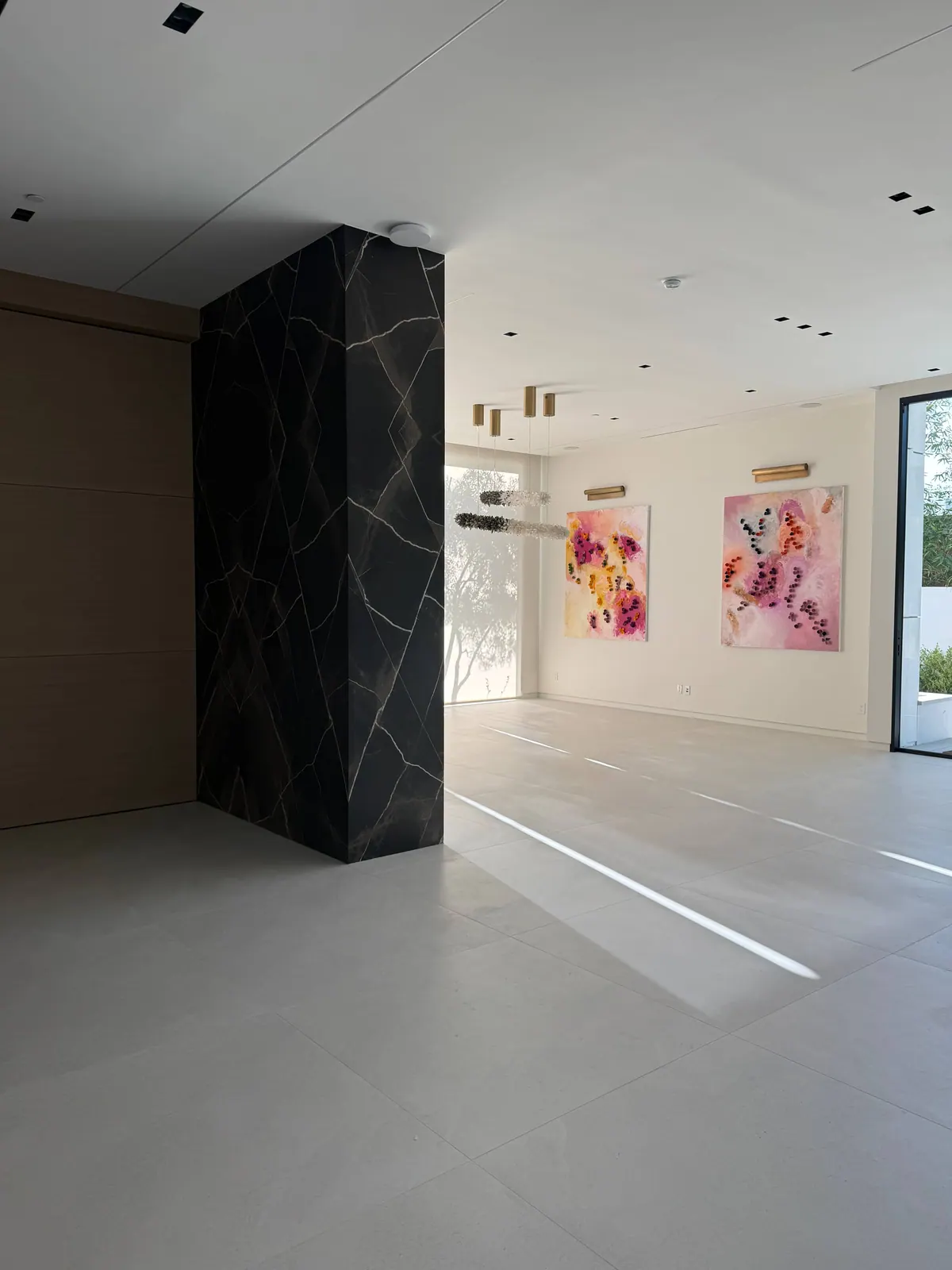 Bright room with a black stone column and two framed floral paintings.