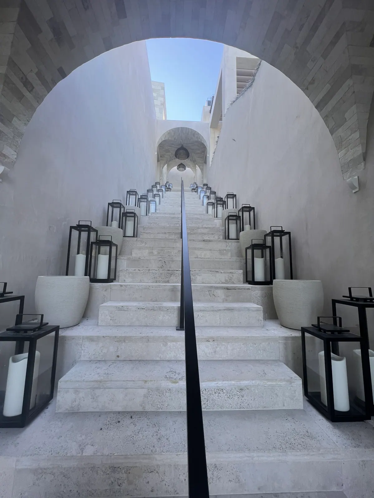 Stone stairway with lanterns on each step, leading through an arch.