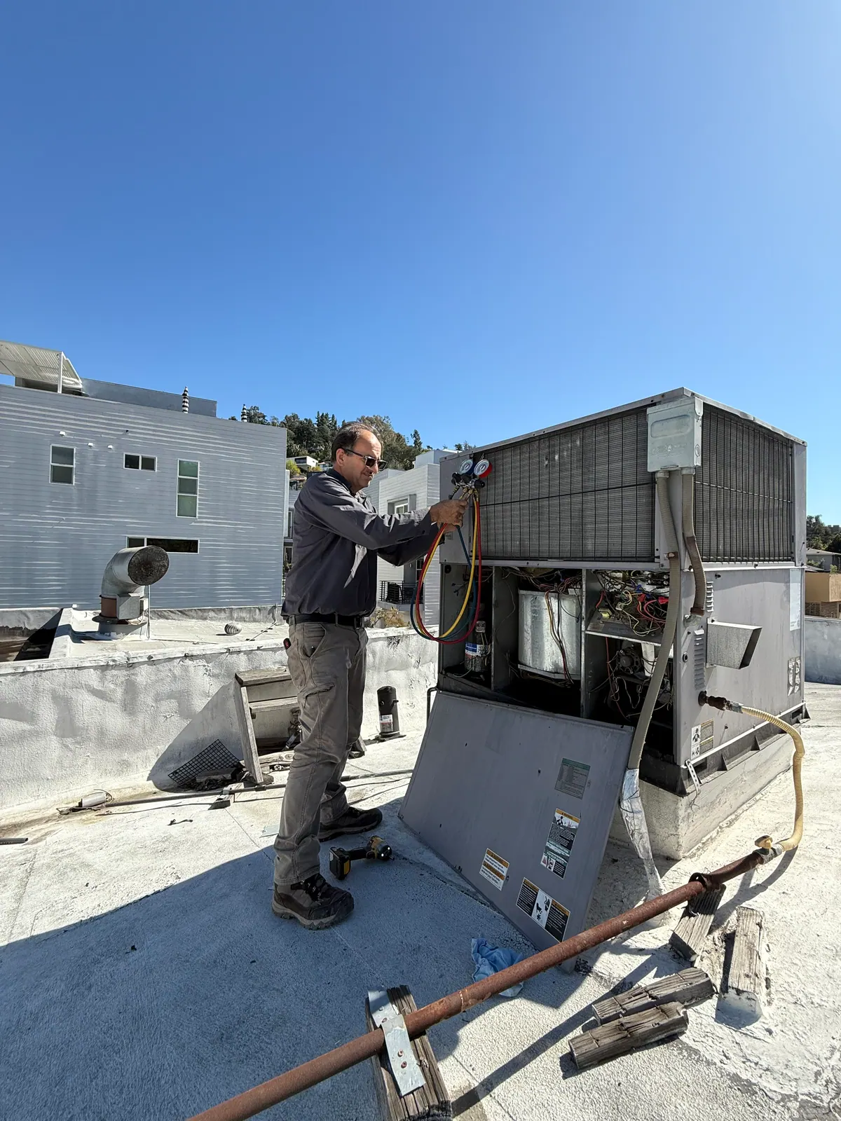 Air Plus HVAC technician working on an open rooftop unit.