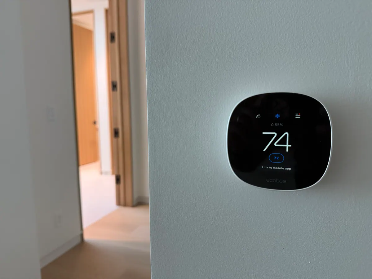 Wall thermostat showing 74 degrees on a gray wall.