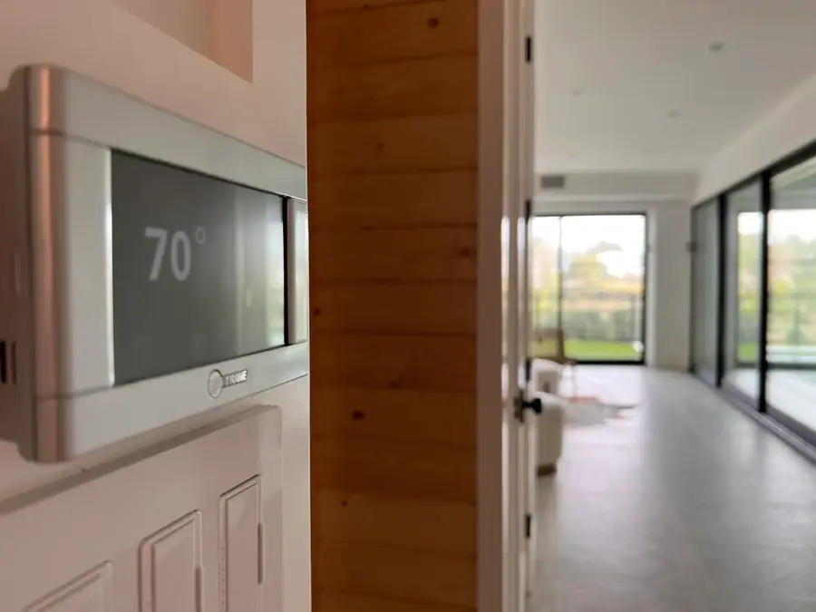A wall thermostat reading 70 degrees beside a wood-paneled doorway.