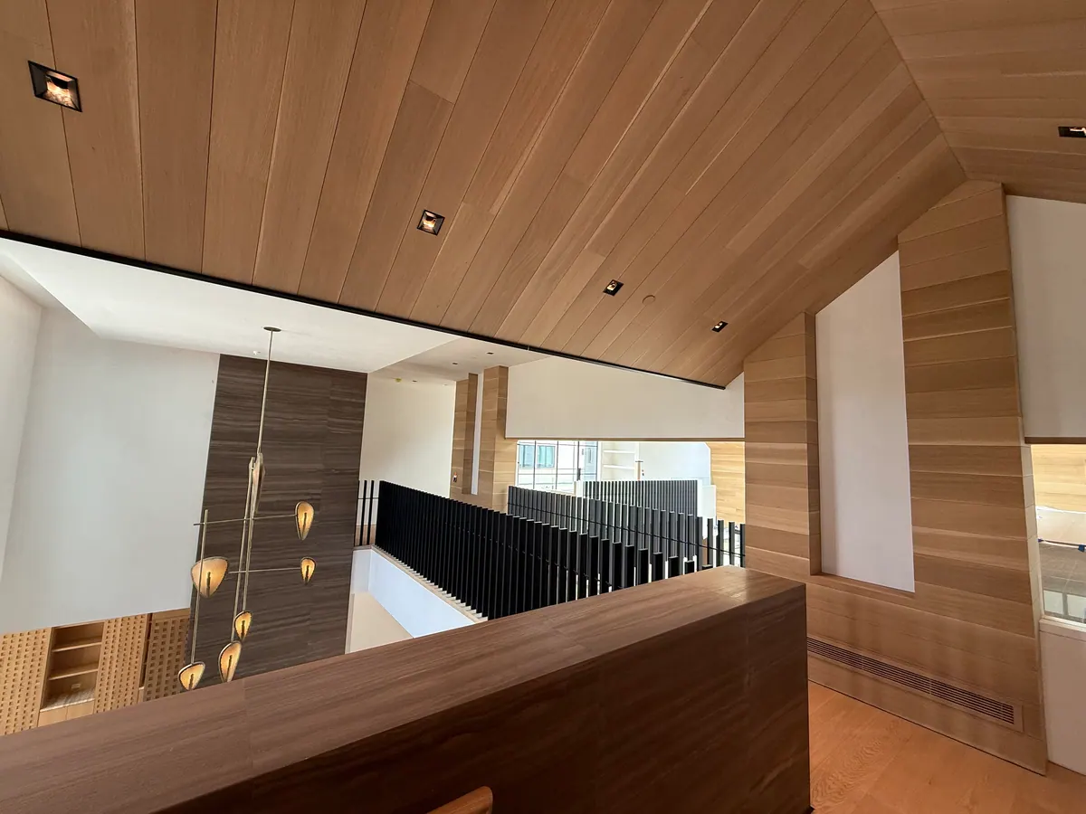 Upper landing with an oak plank ceiling, hanging pendants, and a black railing.