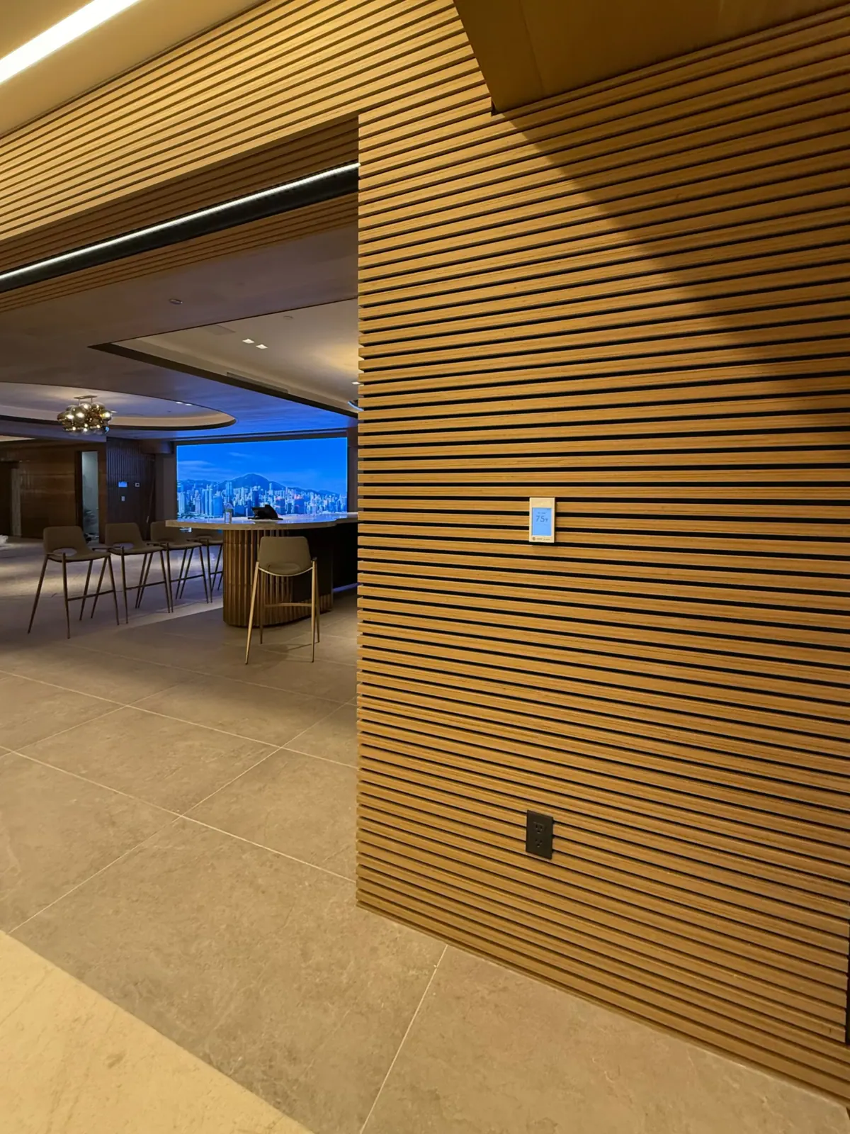 Wood-slat wall with an opening to a large lounge beyond.