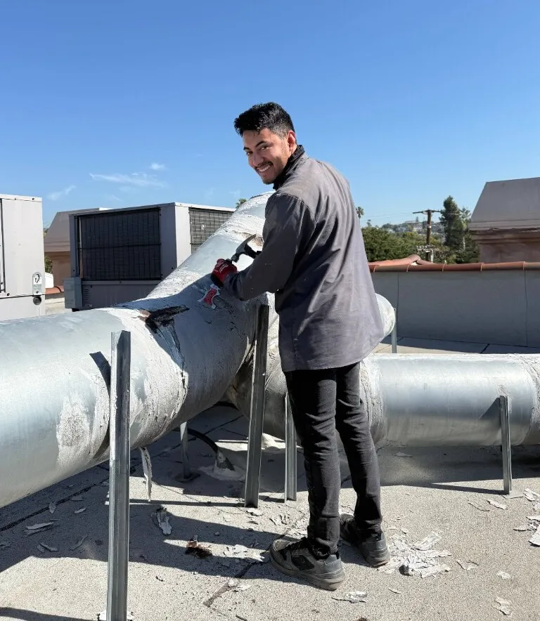 A technician removing insulation from large rooftop ducts.