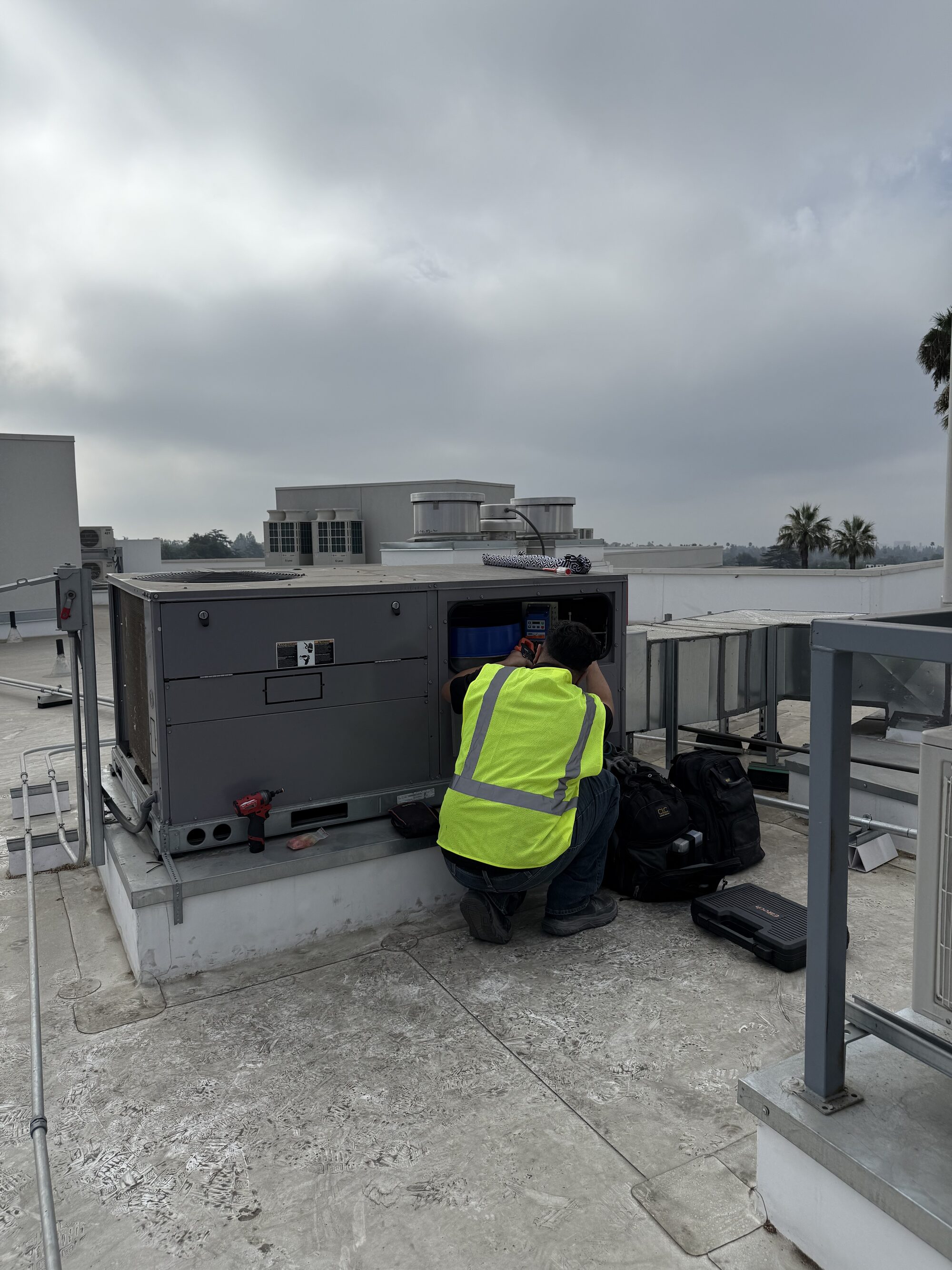 Air Plus technician repairing a commercial rooftop HVAC unit
