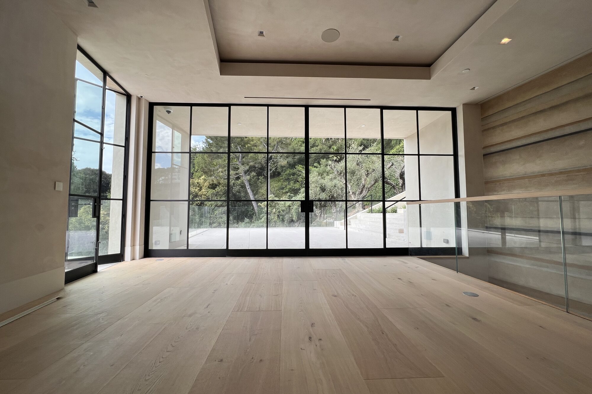 Room with a glass wall looking onto trees.