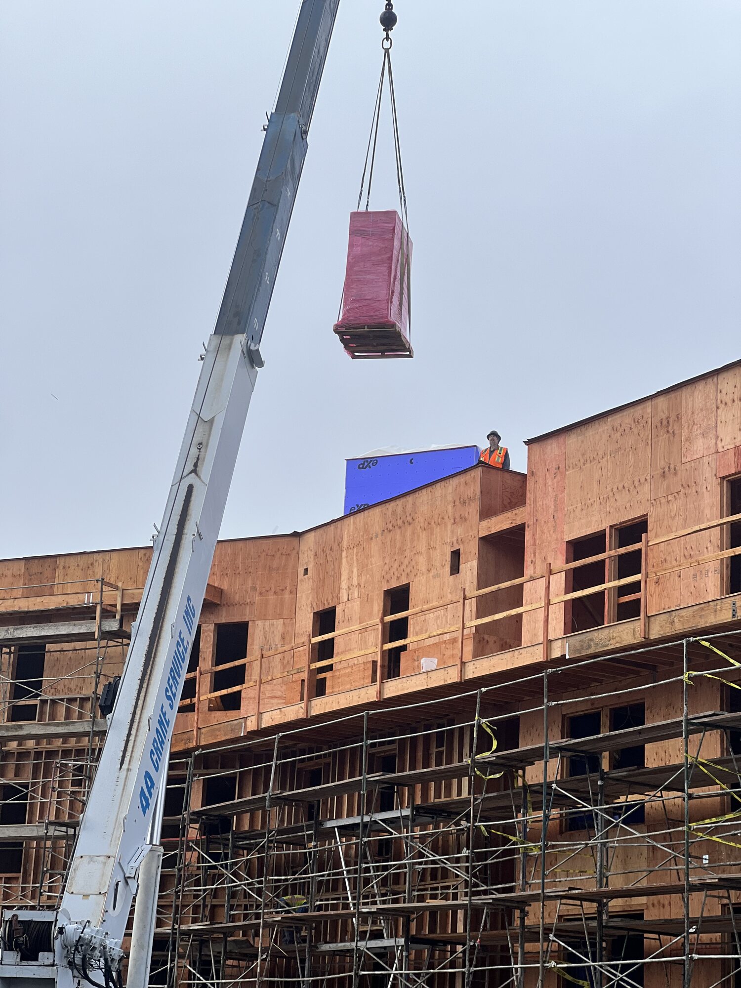 Crane setting a new HVAC unit on a commercial building roof