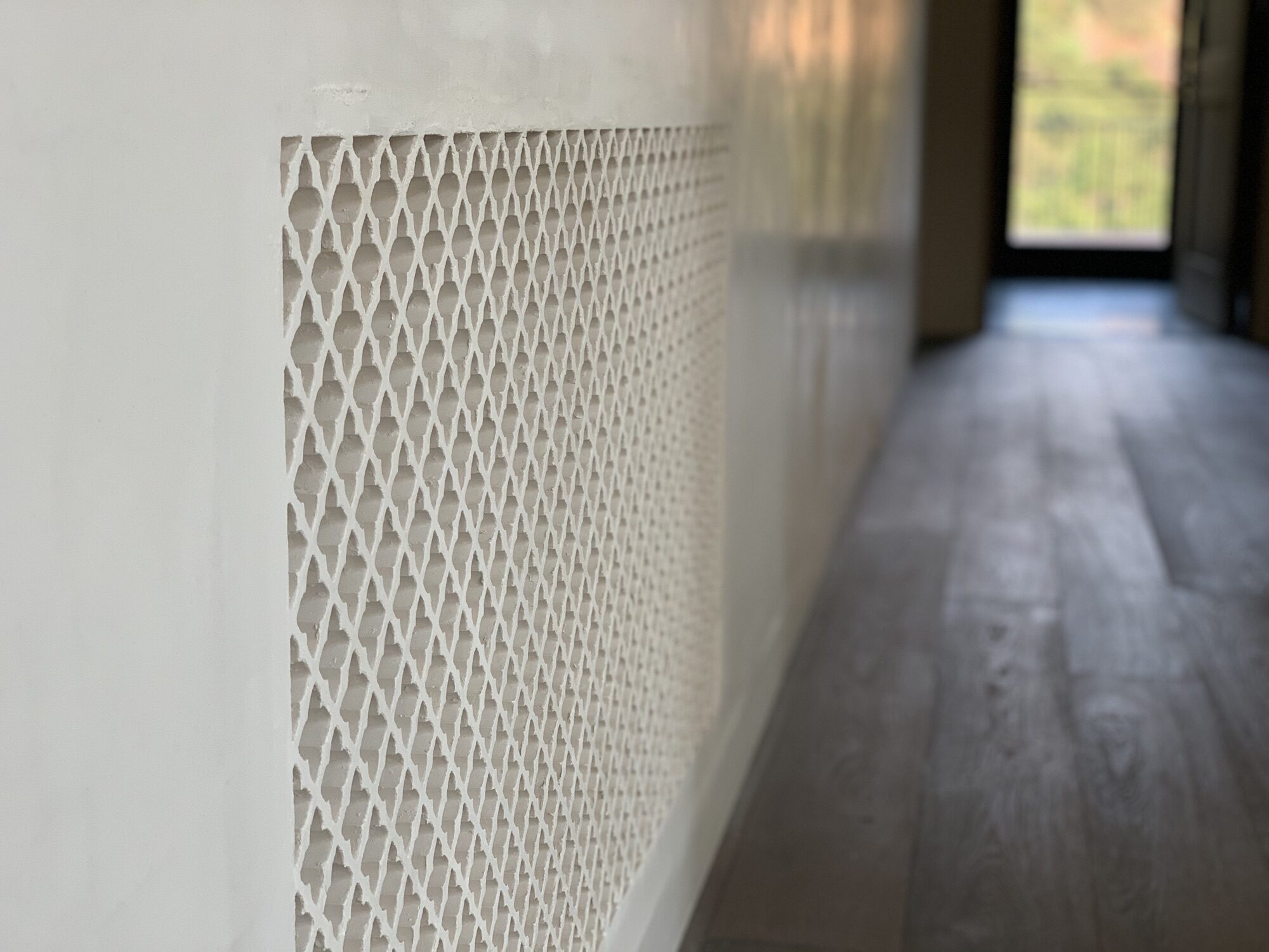 A patterned grille set into a hallway wall.