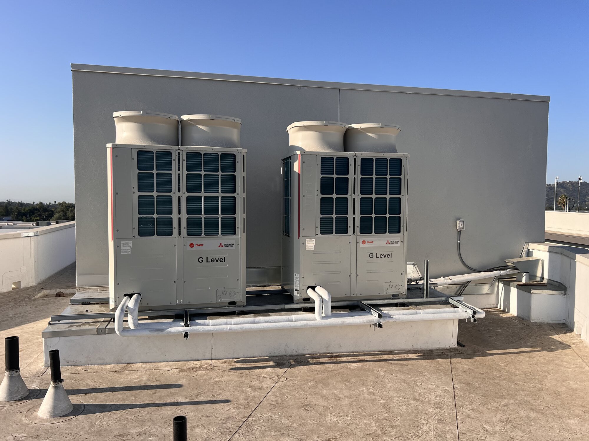 Mitsubishi Electric and Trane outdoor HVAC units on a commercial rooftop
