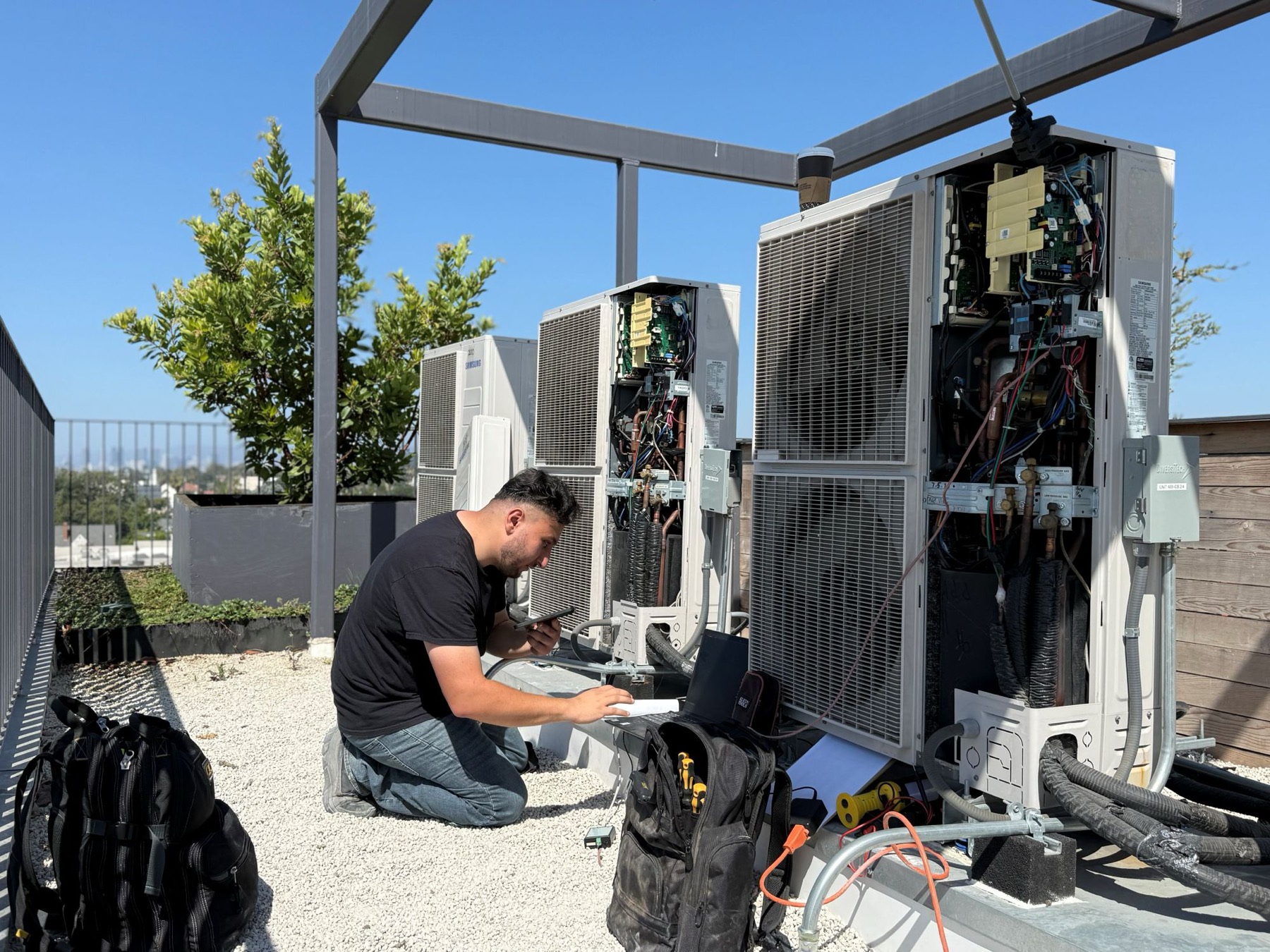 Technician checking the controls on an open rooftop unit.