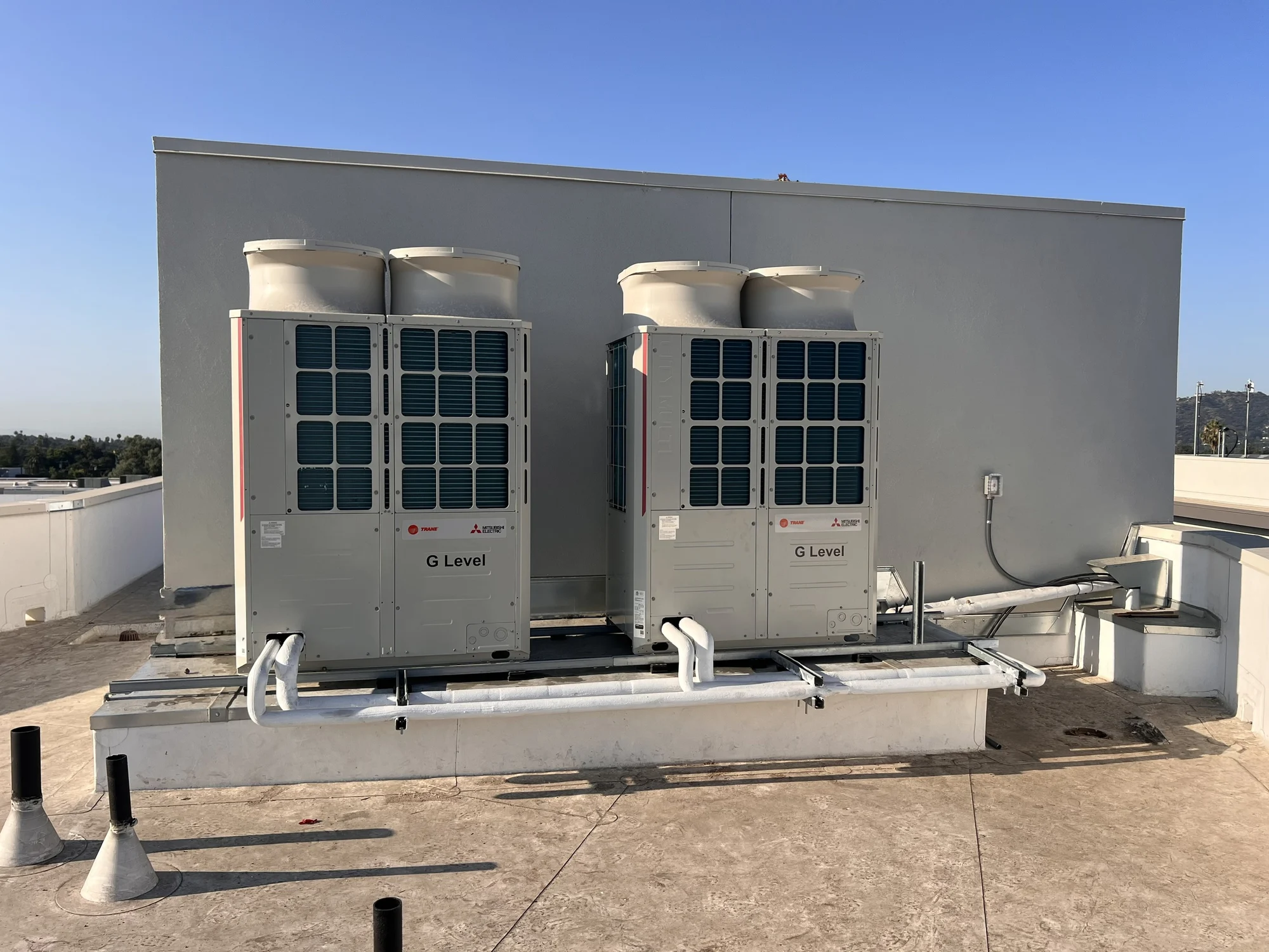Two Trane and Mitsubishi Electric VRF outdoor units on a commercial rooftop.